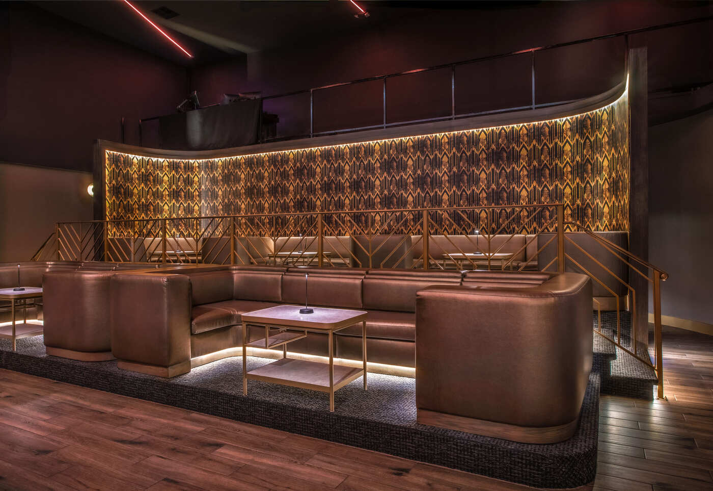 Luxurious seating area at Zouk Los Angeles featuring tiered leather booths, gold railings, and a geometric illuminated wall backdrop.