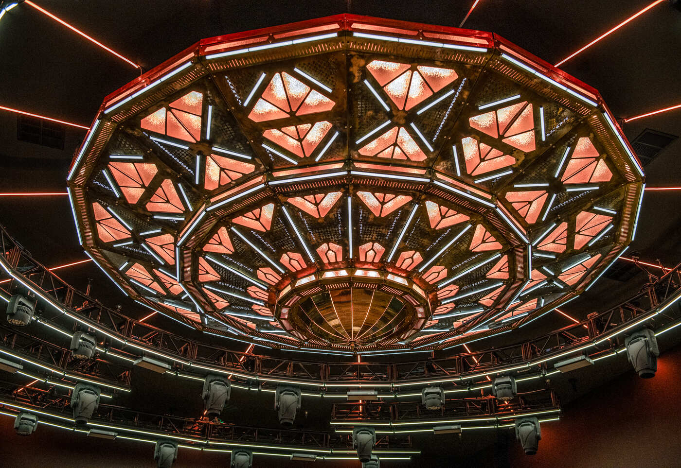 Geometric LED ceiling installation with glowing red and white lights in a circular pattern at a nightclub.