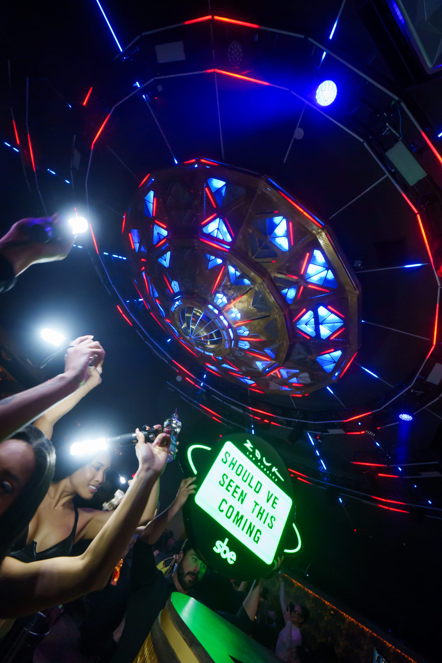 Clubgoers holding up signs and sparklers under a vibrant, futuristic ceiling at Zouk Los Angeles.